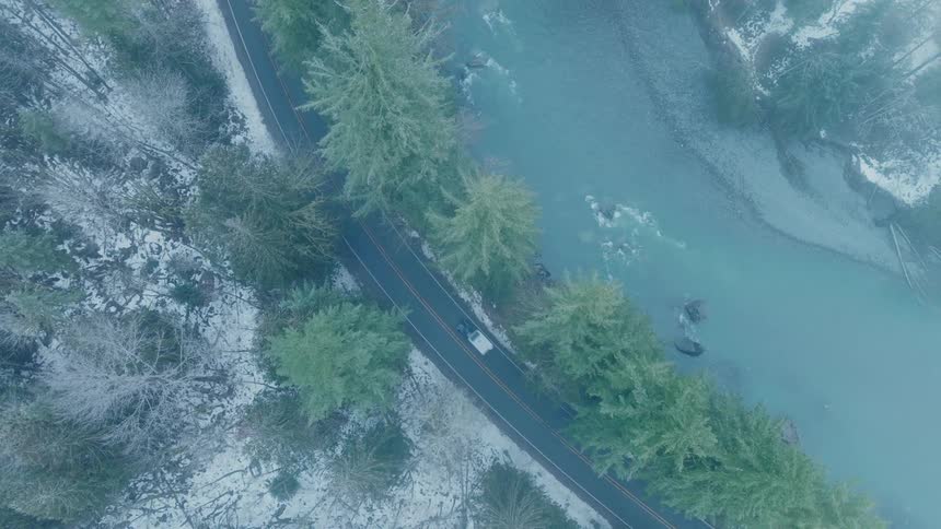 Aerial panorama of a road along a river and between snowcovered mountains