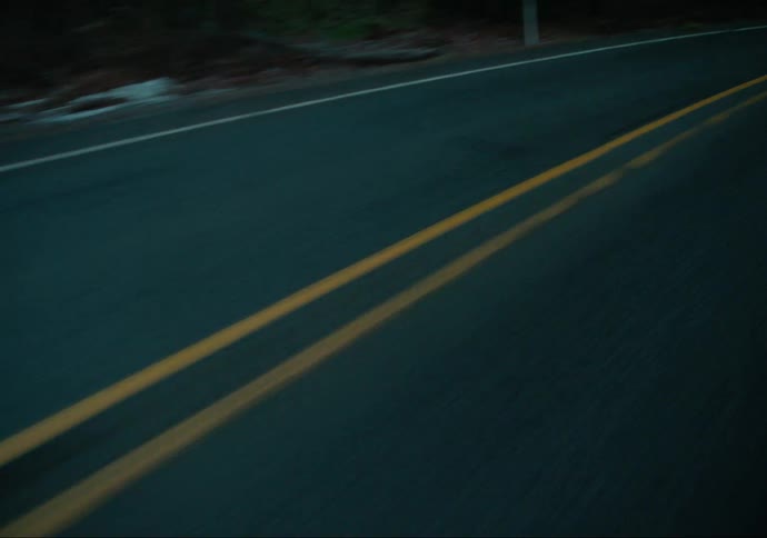 A pickup truck with a camper shell is driving on a road