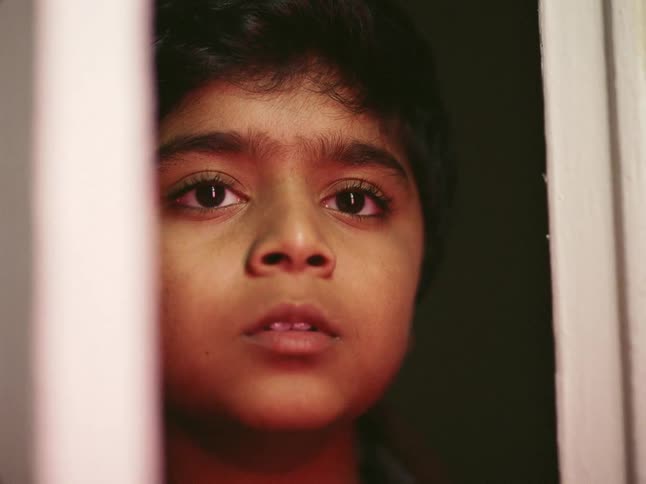 Close up of the face of a boy looking out the window