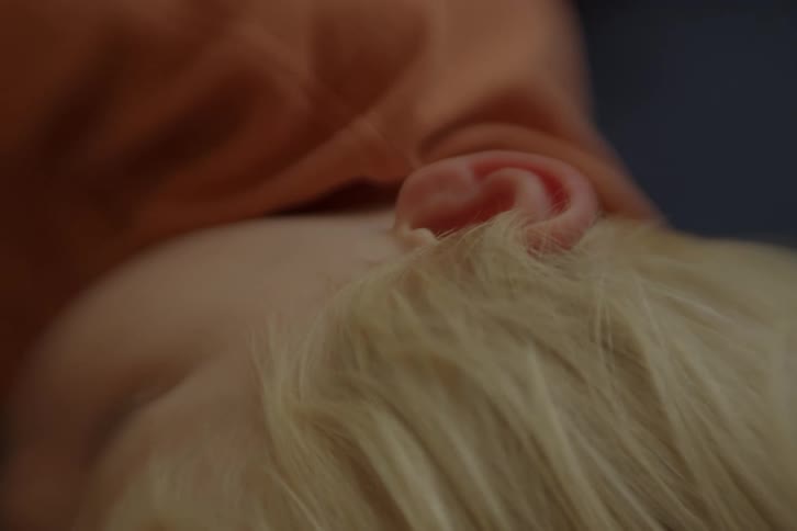 A close up of a blonde boy sleeping, ear in focus