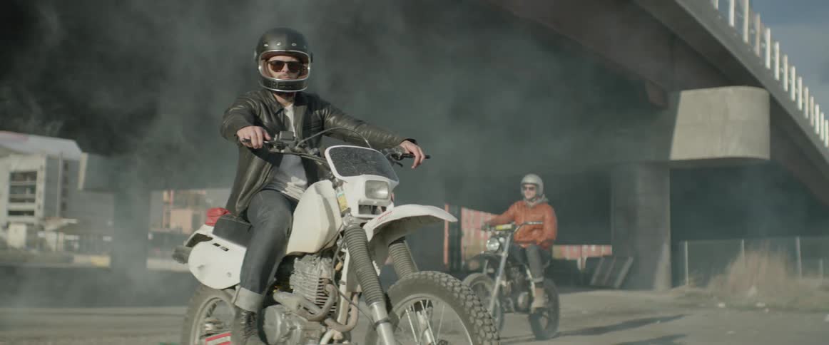 Two motorcyclists sitting on their dirt bikes under an overpass