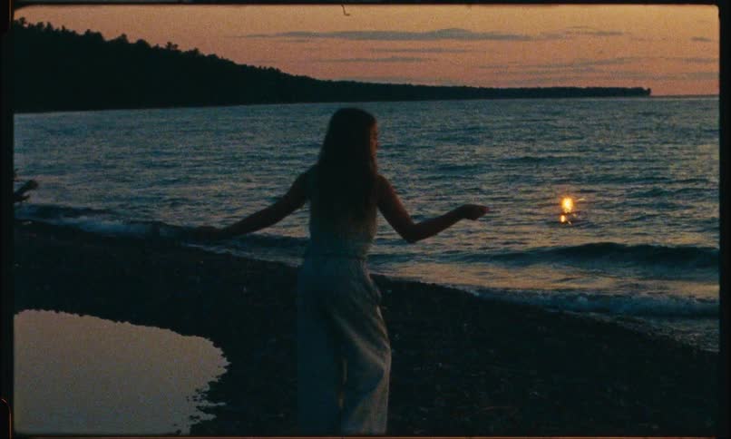 A female waving around a sprinkler firework at dusk