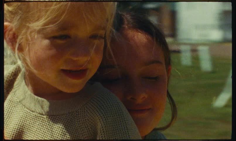Two little girls are hugging and smiling while the room behind them is spinning