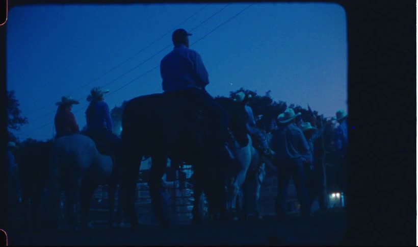 Cowboys gather on a rodeo at night caught on vintage film