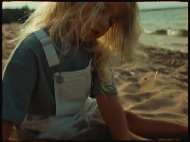 Blonde girl plays in the sand on the beach