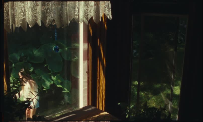 Girl playing in the garden seen from a window in the house