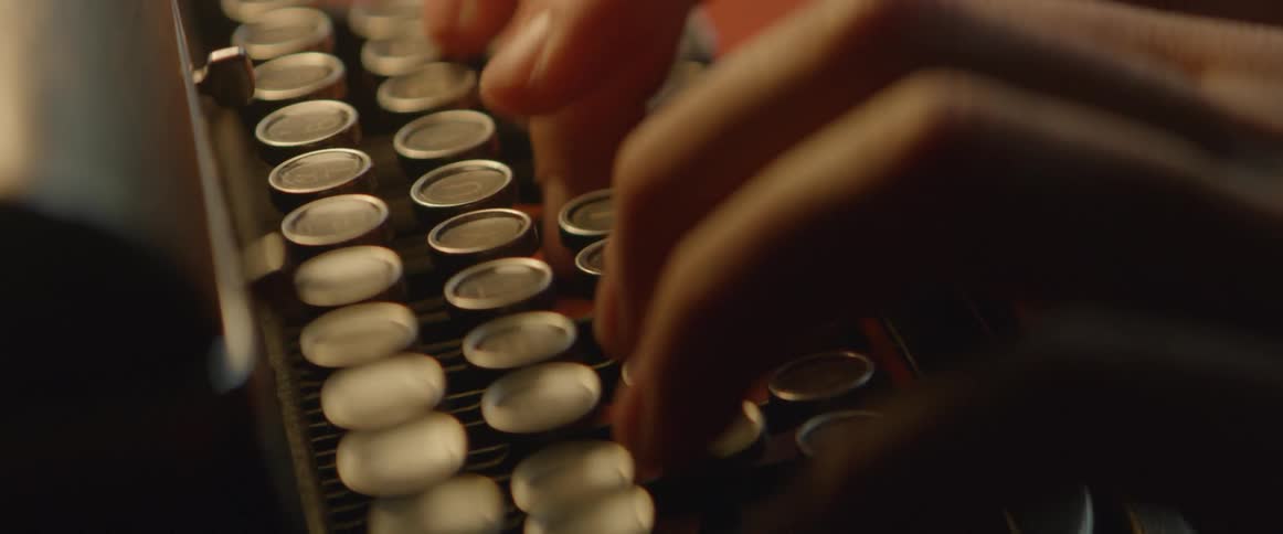 Fingers push keys of an old typewriter
