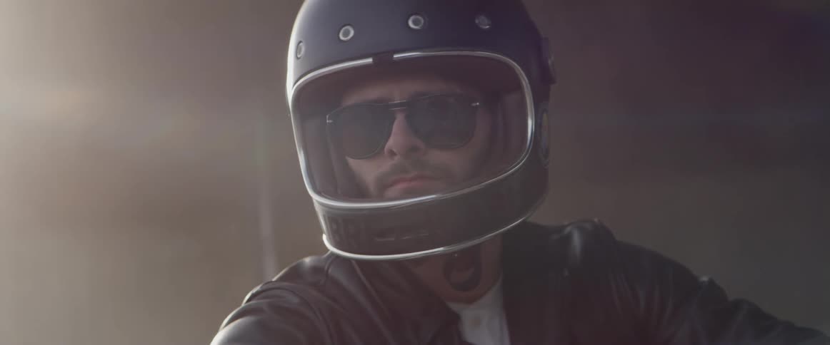Man wearing sunglasses and helmet waits in swirling smoke