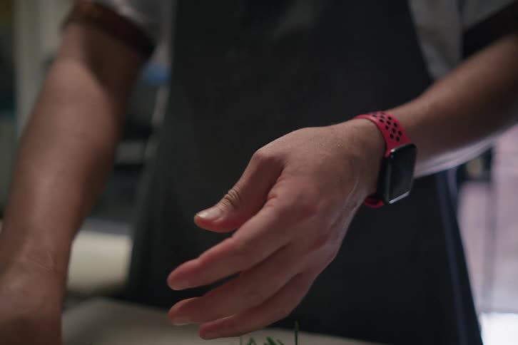 A man ripping up garnishes to be added to food at a restaurant