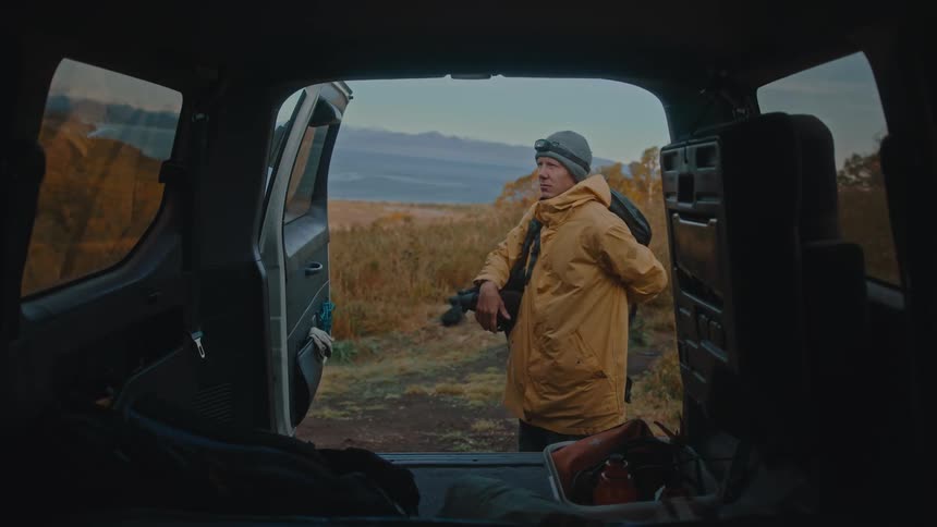 A man getting a backpack out the back of an suv