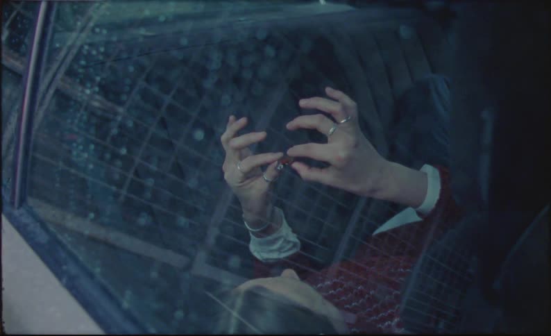 A woman lying in the back seat of a car playing with a small colorful object