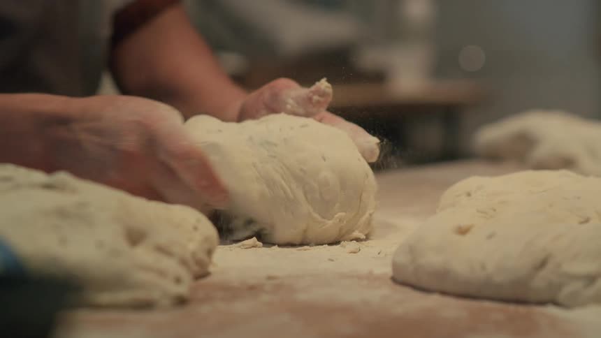 Close up of a person kneading dough over a table