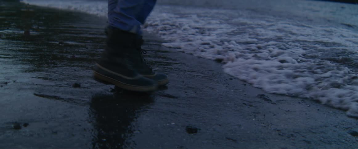 A man steps back from the surf
