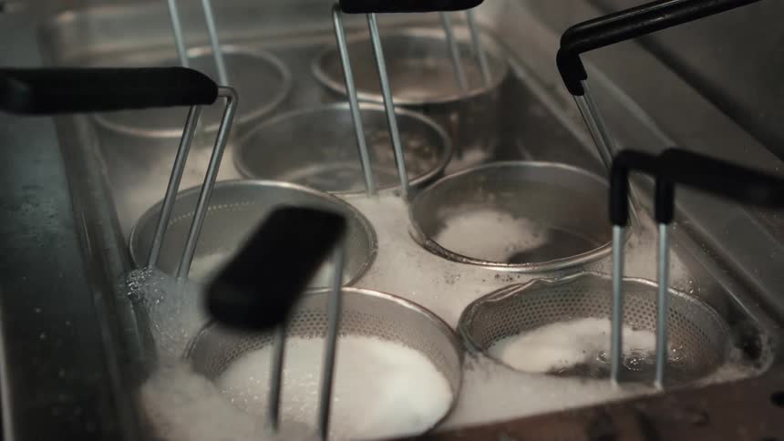 A closeup of metal containers with holes in boiling water