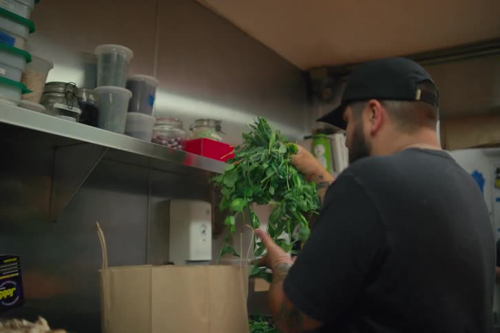 Man working in a restaurant kitchen selecting fresh herbs