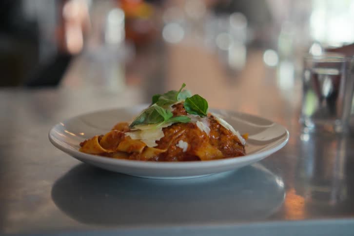 A closeup of a pasta dish served on the counter of a restaurant