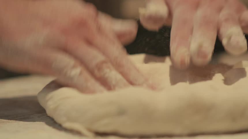 A person making some pizza dough on a table