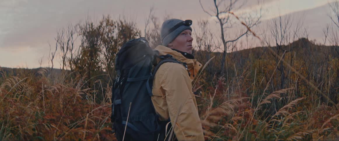 A man lost in a meadow during a cloudy sunset
