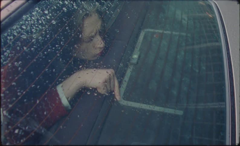 A clip of a lady in the back of a car