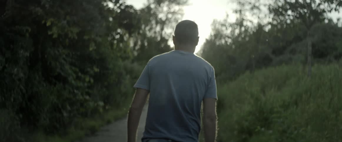 A man is walking down a path surrounded by trees