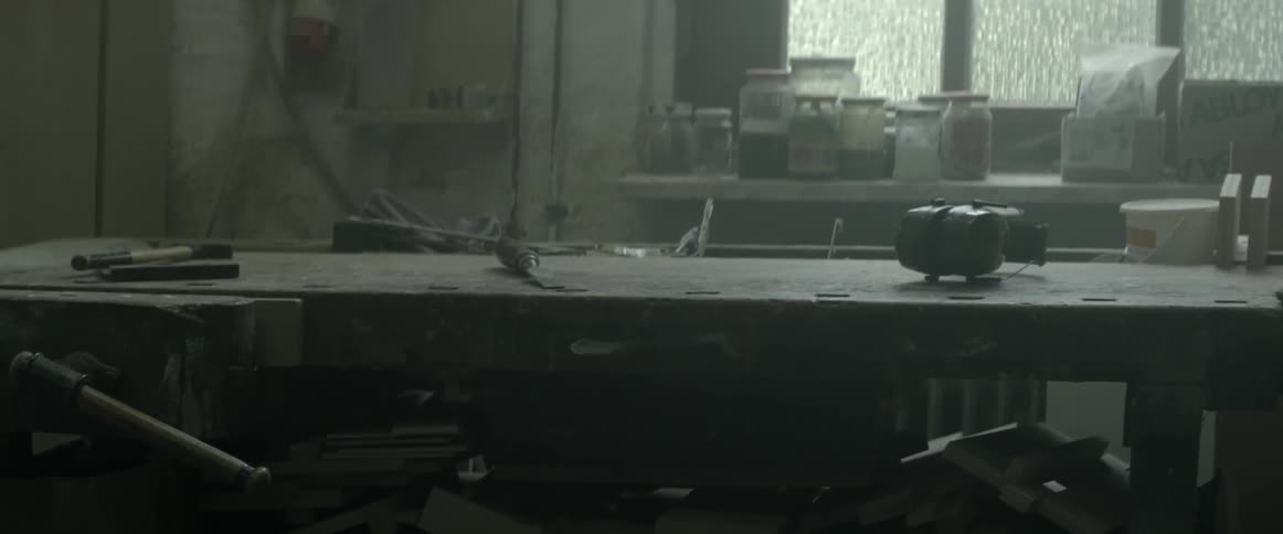 A couple tools sit on a dusty table in a workshop