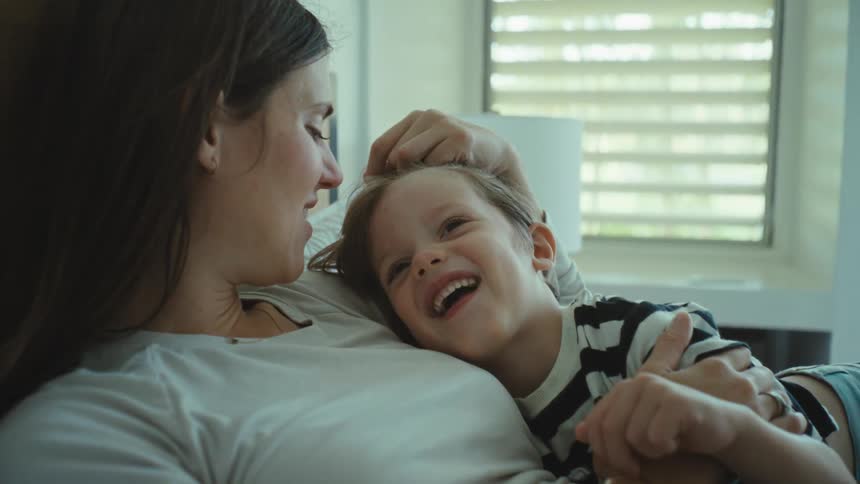 Mother and son cuddling in bed talking