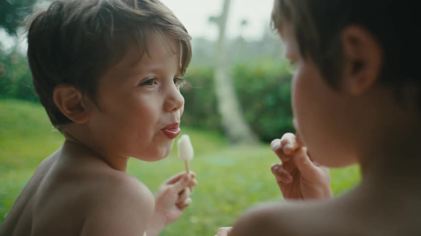 Brothers eating popsicles in the backyard