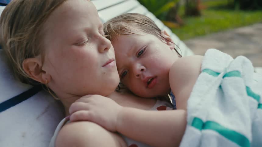 Two children lay together in the yard