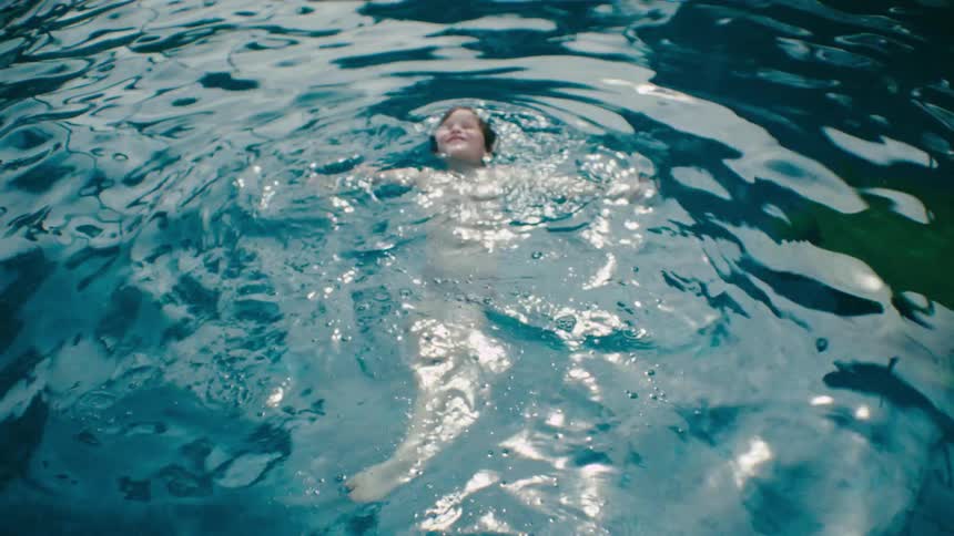 Boy struggles while swimming alone in a swimming pool