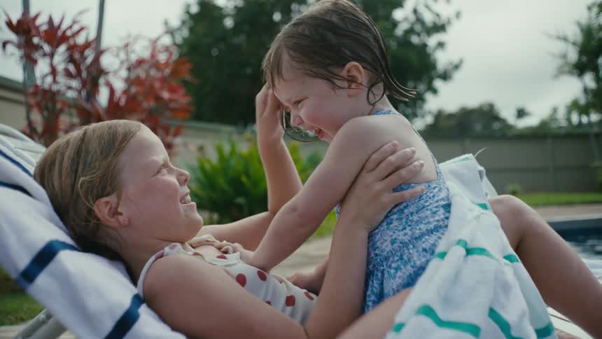 Sisters tickling each other next to the swimming pool