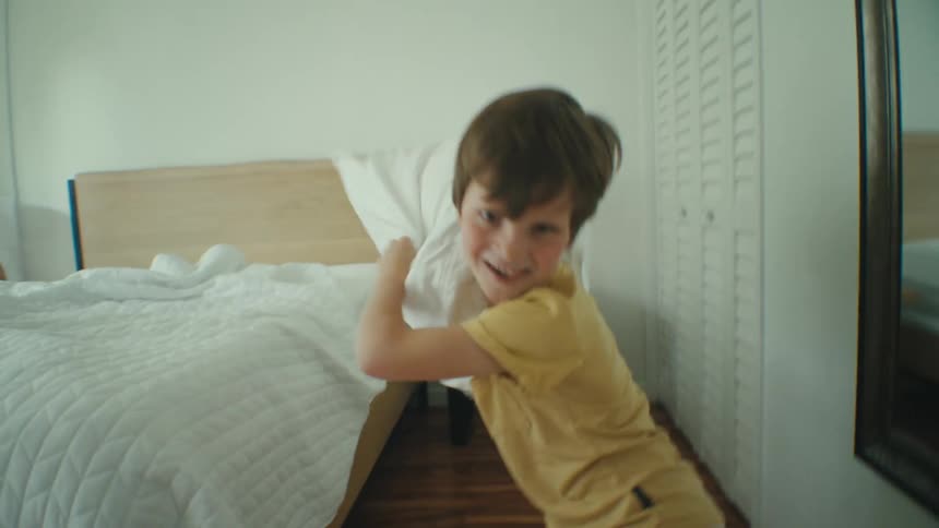 Boy in the bedroom pillow fights with the camera