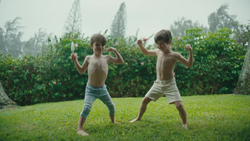 Siblings dancing in the backyard while eating popsicles