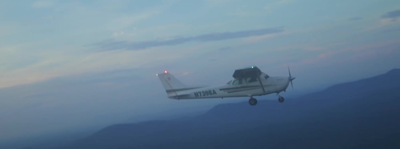 A small plane flying through the sky at dusk