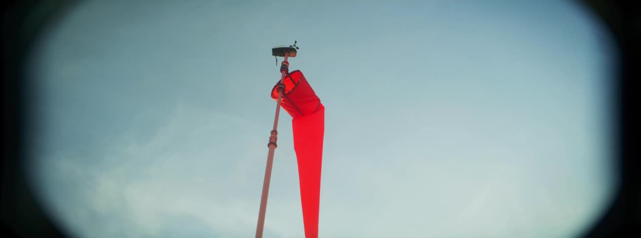 A bright orange windsock hanging from a pole