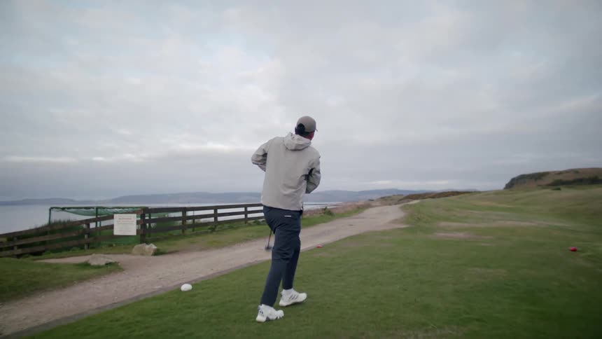 Asian man playing golf swings his club