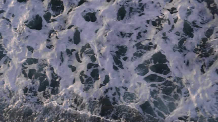 Aerial view of ocean waves illuminated by sunlight