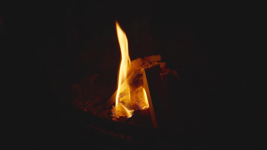 Close up of a person starting a campfire at night