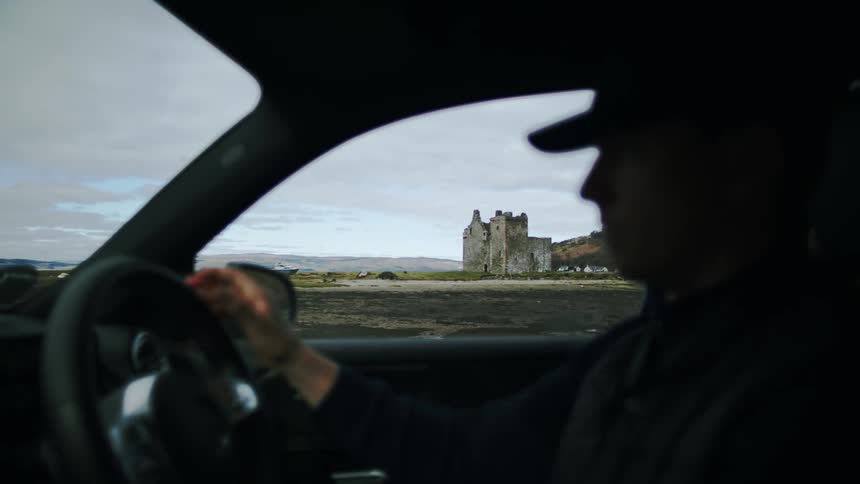 A man driving a car down a road in a rural area