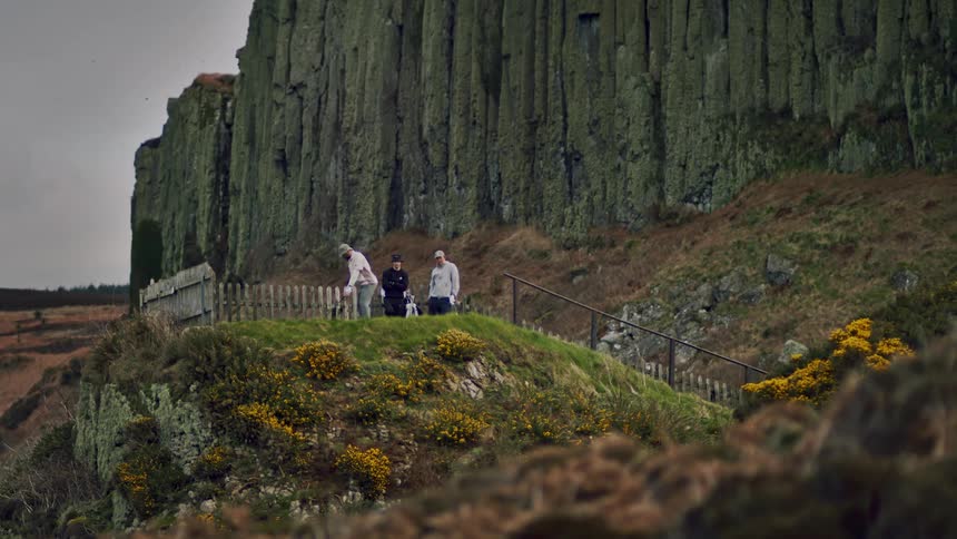 Three golfers golfing near a large mountain