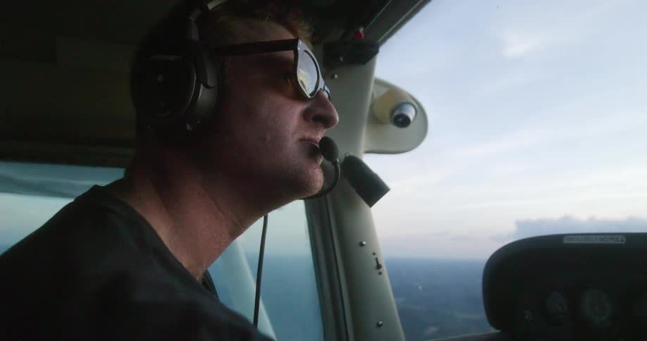 Pilot wearing headphones looks out plane window