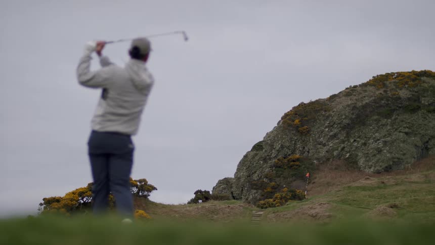 Man playing golf near a hill