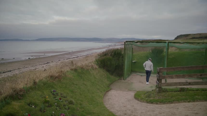 A man is playing golf on a course near the beach