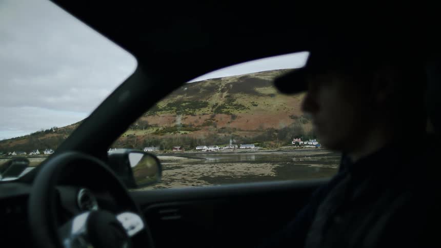 A man driving through a coastal town during sunset