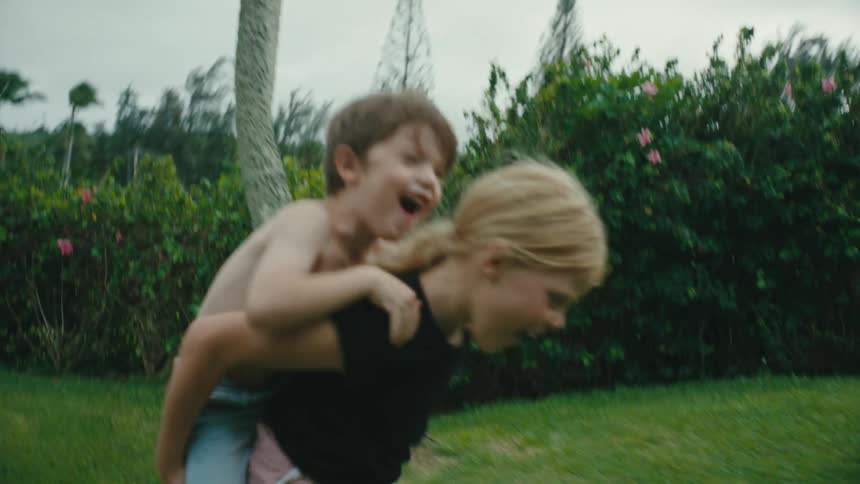 A boy is getting a piggyback ride in the yard