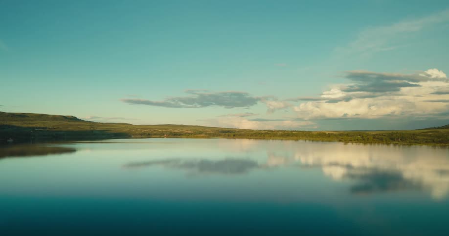 A placid landscape with a lake reflecting the clouds