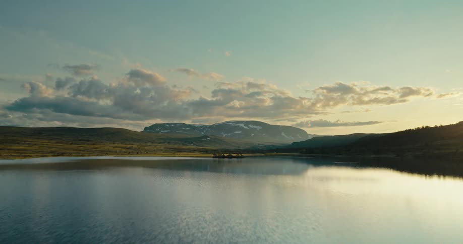 A serene scene of a lake with mountains in the distance at sunset