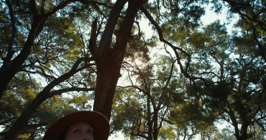 A clip of a lady putting on a hat in the woods