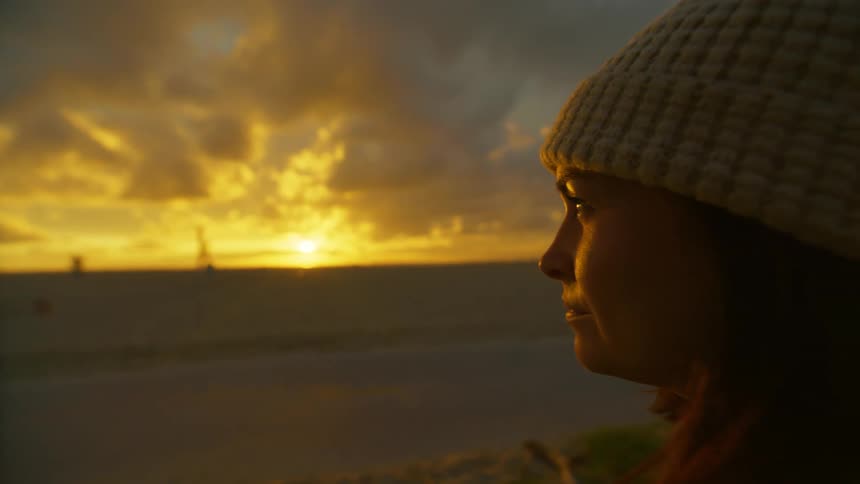 A woman watches the sunrise on the beach