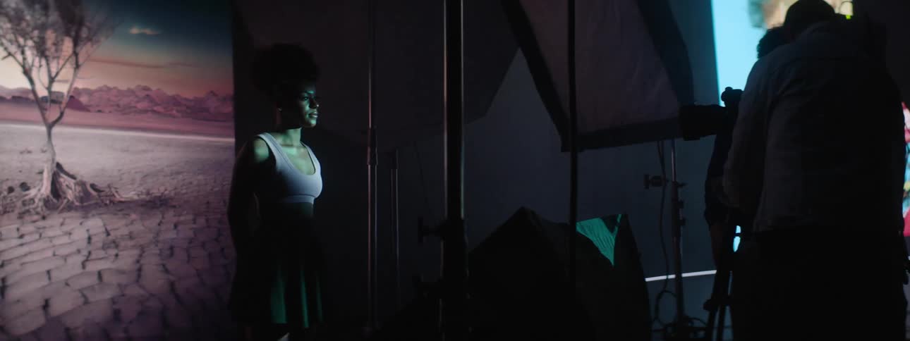 Photographer takes pictures of a model in front of a large projector in the background