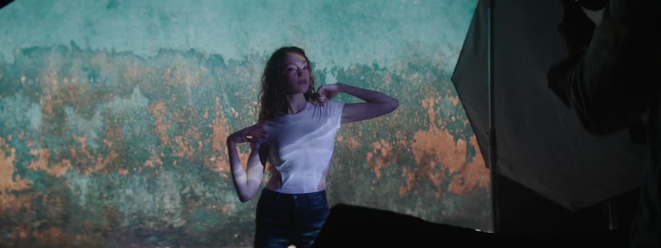 A female model poses in front of a large screen with many images projected onto it